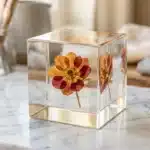 Fleur séchée orange et rouge encapsulée dans un cube de résine claire